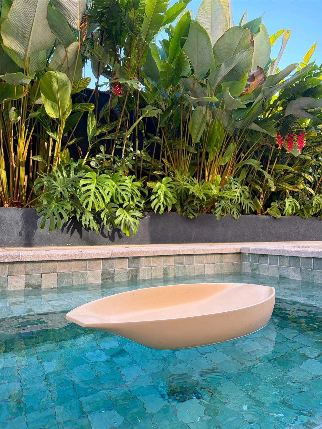 Peça Canoa flutuando em uma piscina cercada de folhagens